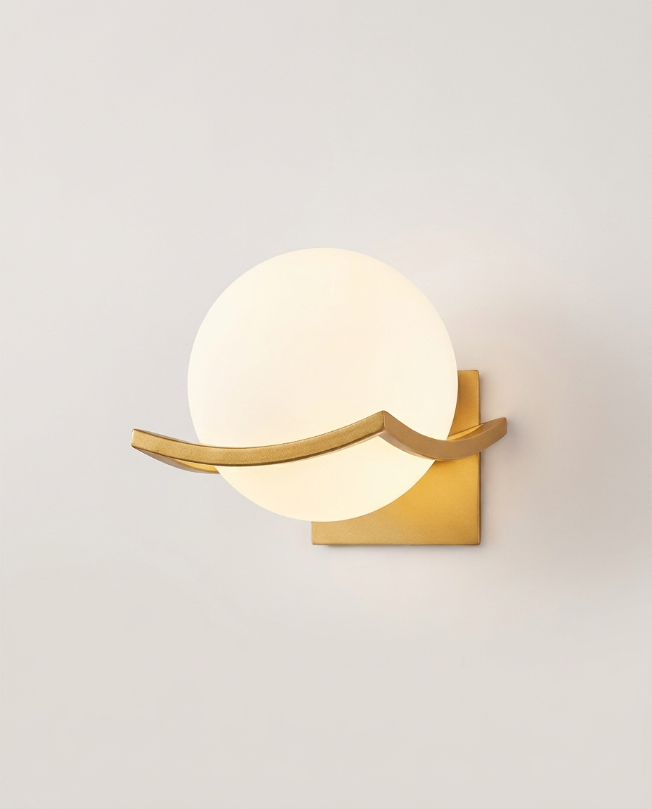 Glass globe wall sconce with gold finish on a clean light neutral studio background